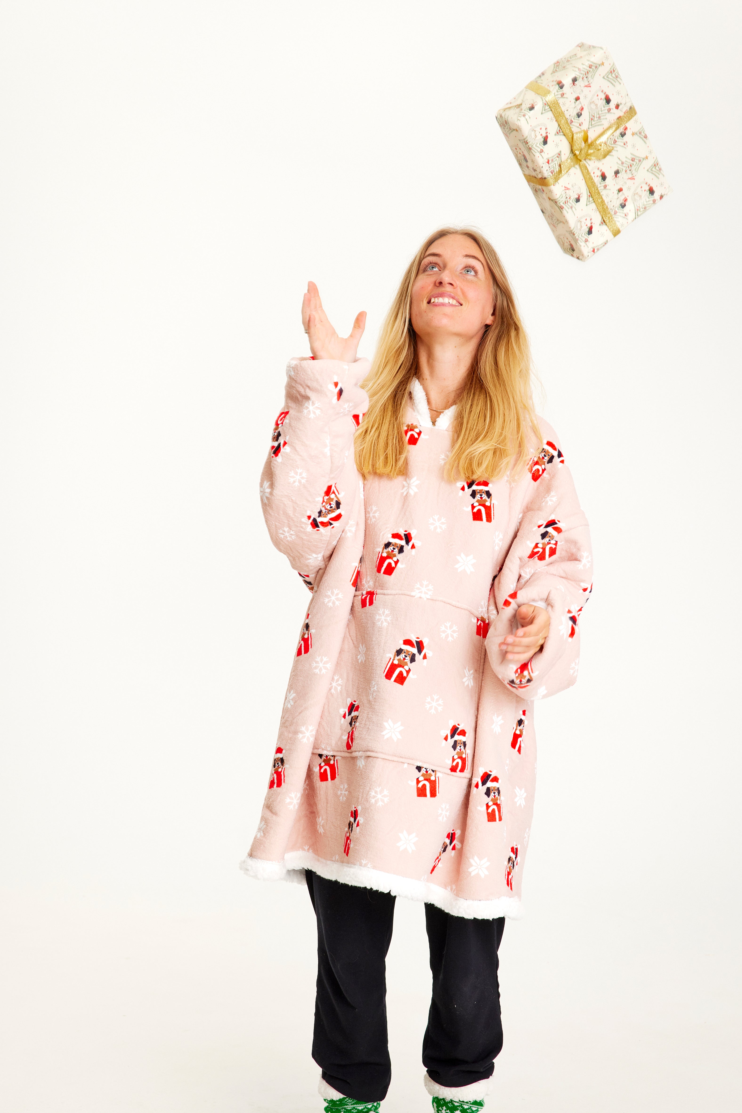 Een vrouw die een cadeau gooit, draagt een roze kersttrui met honden erop.